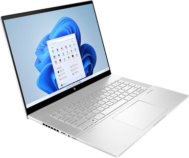 HP Envy 16 laptop with silver finish, visible keyboard, screen displaying Windows desktop, placed on a flat surface.