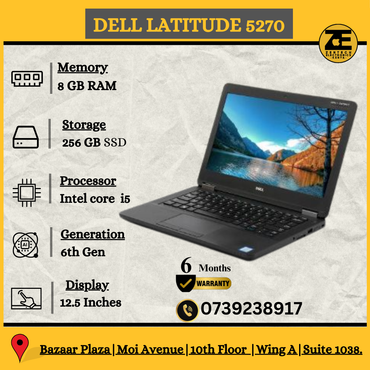 Dell Latitude 5270 laptop with a black keyboard and a display showing a nature wallpaper. The laptop is on a flat surface, likely a desk, in an indoor setting.