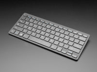 A wireless keyboard with a gray color scheme, featuring a full QWERTY layout and a touchpad.